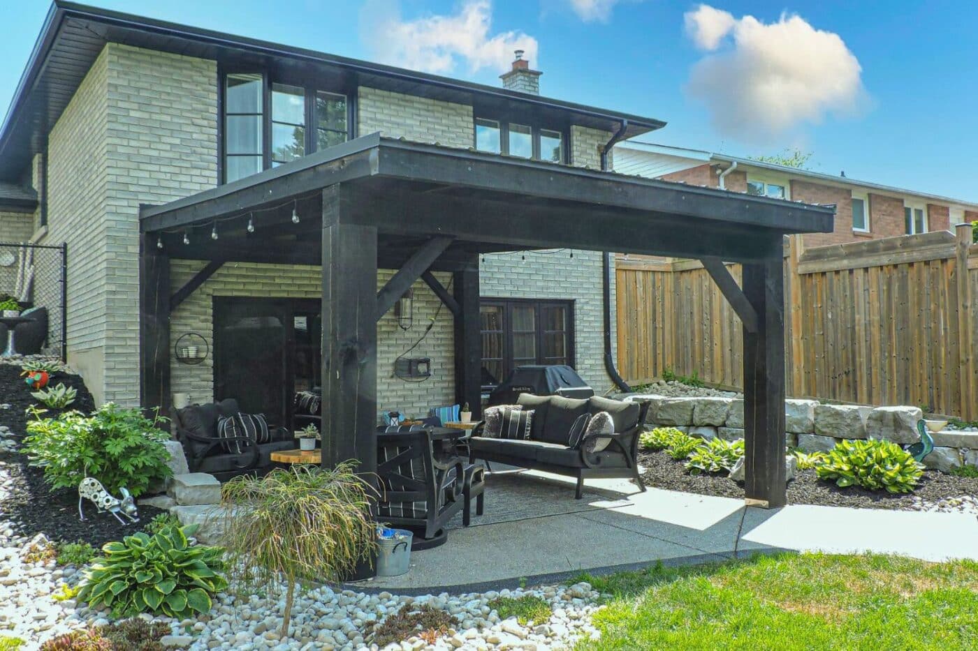 Dark, wooden Pergola in Elyria Ohio over patio and besides garden