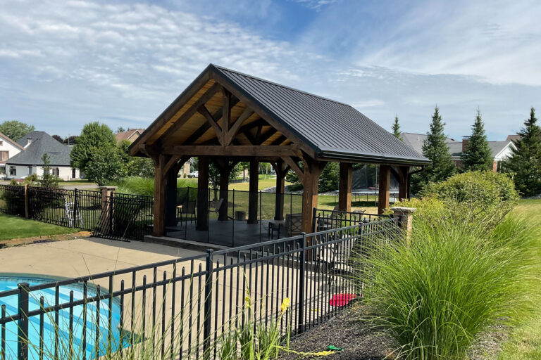 deluxe timber frame pool side pavilion surrounded by fencing and bushes in garden outdoor pavilion ideas